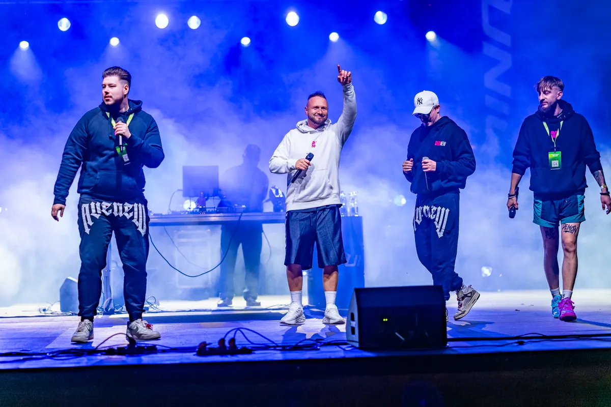Ekipa AVENEW na scenie z ręką uniesioną w górę, w tle DJ przy konsolecie