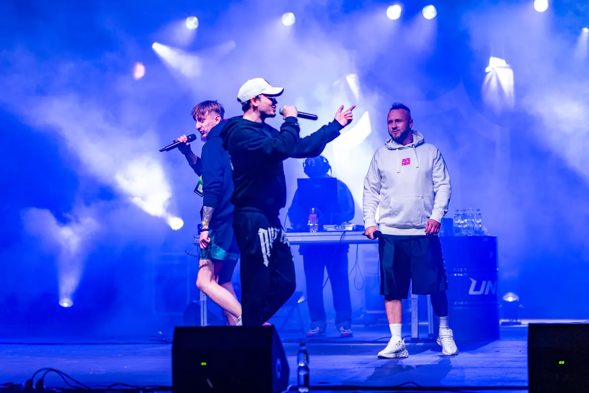 Dwóch wokalistów AVENEW z przodu sceny, w tle DJ przy konsolecie i niebieskie światło